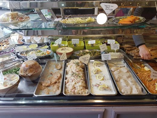 Étal de plats cuisinés du jour, choucroute, filets de poisson à la crème et riz à la paella en plats inox