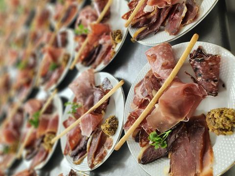 Assiettes de charcuterie dressées en série, jambon sec, saucisson, coppa et tapenade avec une gressin